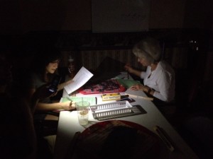 Sara Boykan and Lynn Hall complete their game during a power outage with the help of a friend holding a cell phone torchlight.